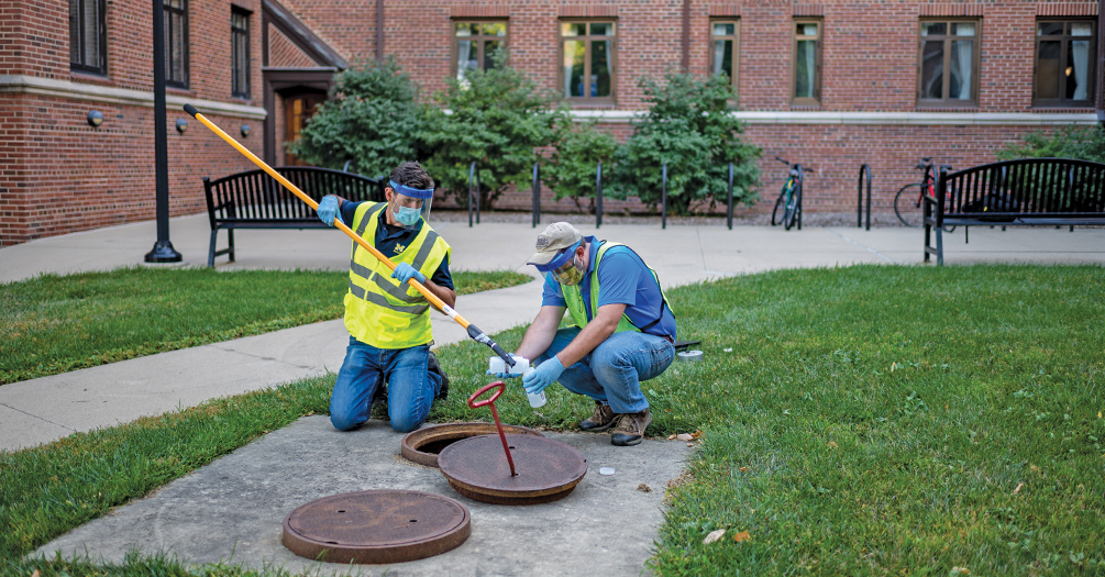 Anthony Shourds, soil erosion and sedimentation control specialist, and Philip Szorny, environmental engineer—both with the university’s Environment, Health, and Safety Department—collect sewage samples on the University of Michigan campus to test for coronavirus.