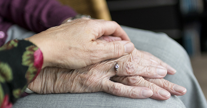 hands of caregiver and an elderly woman