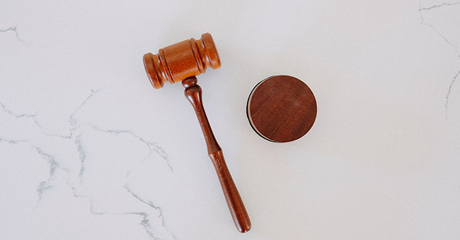 A wooden gavel is places on a white marble surface.