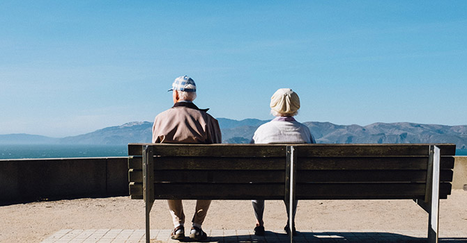 Older couple sitting on a bench outdoors.