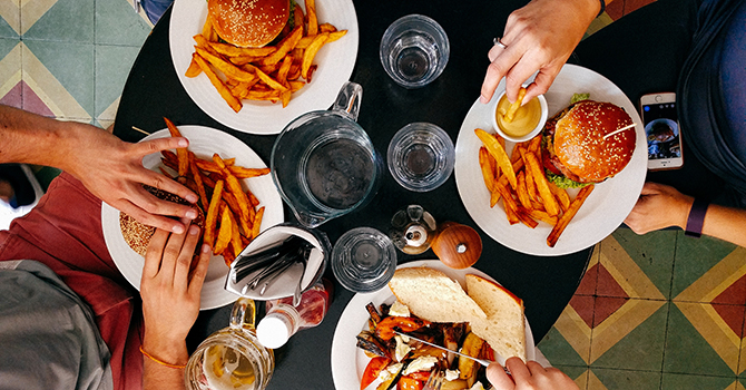 Overhead shot of a group of people passing food around a table at a restaurant.