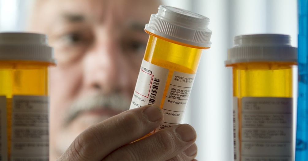 A man looks at a bottle of medication.