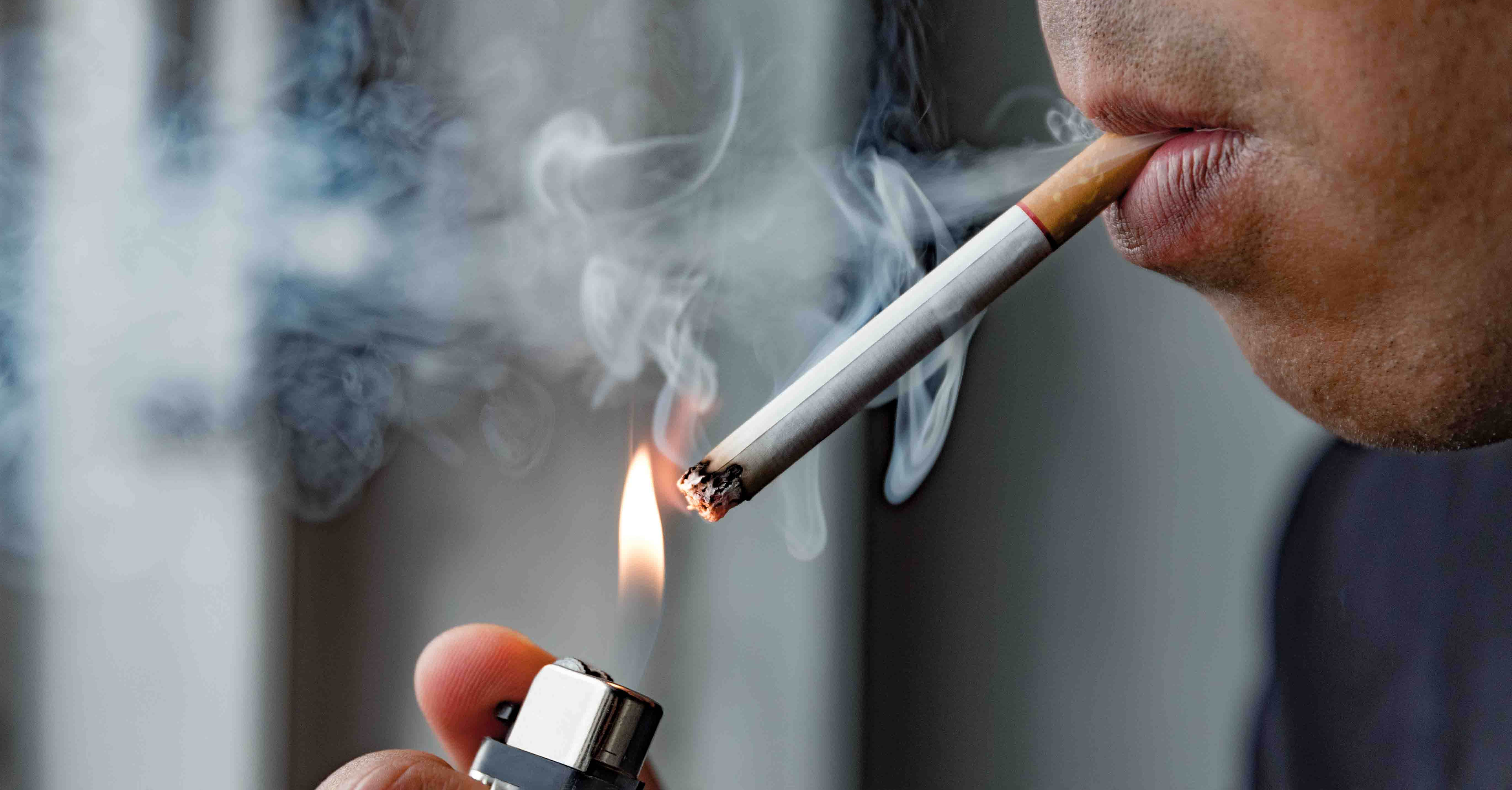 A closeup image of a male lighting a cigarette.
