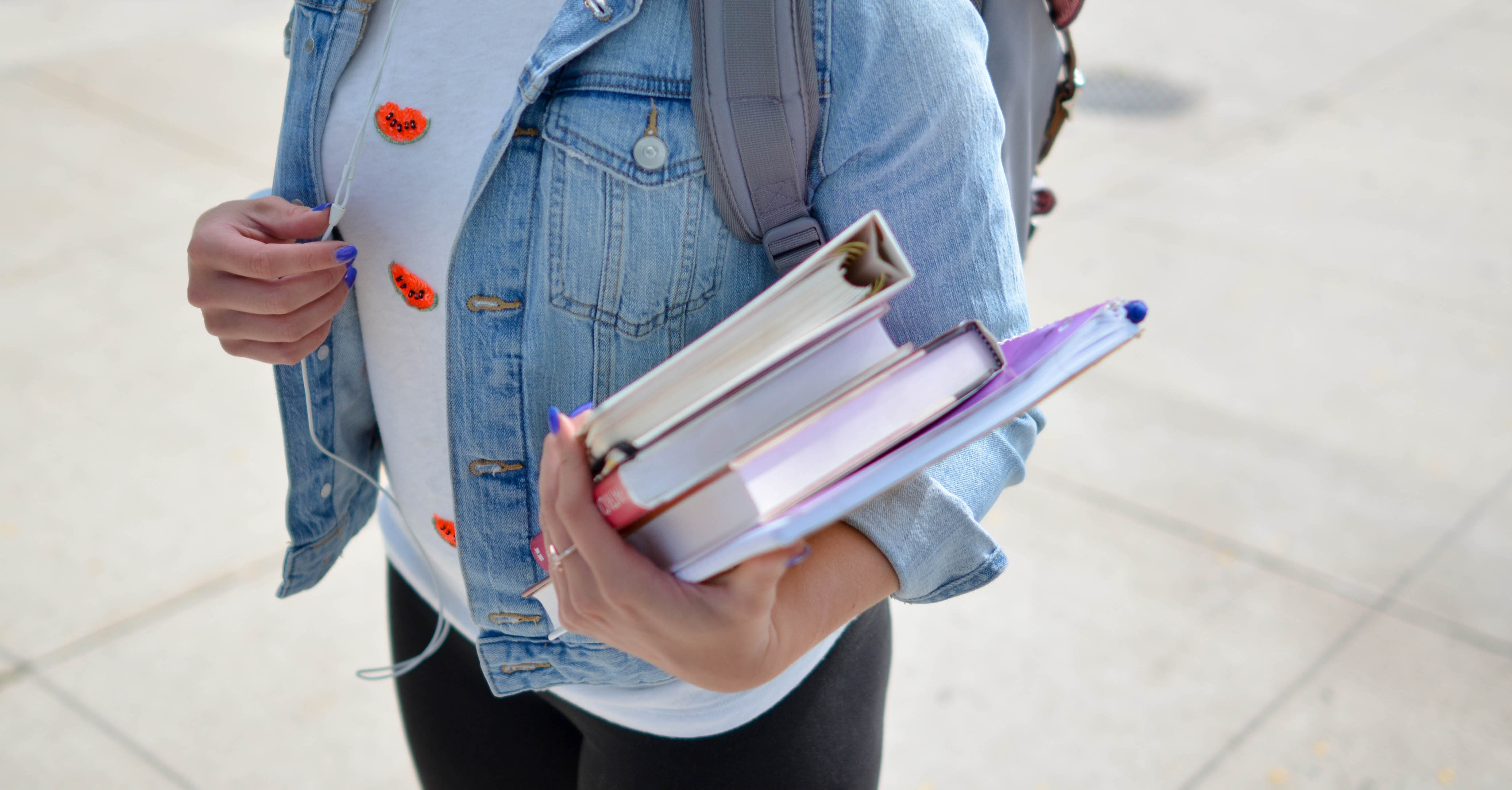A female student wearing a backpack and carrying books.