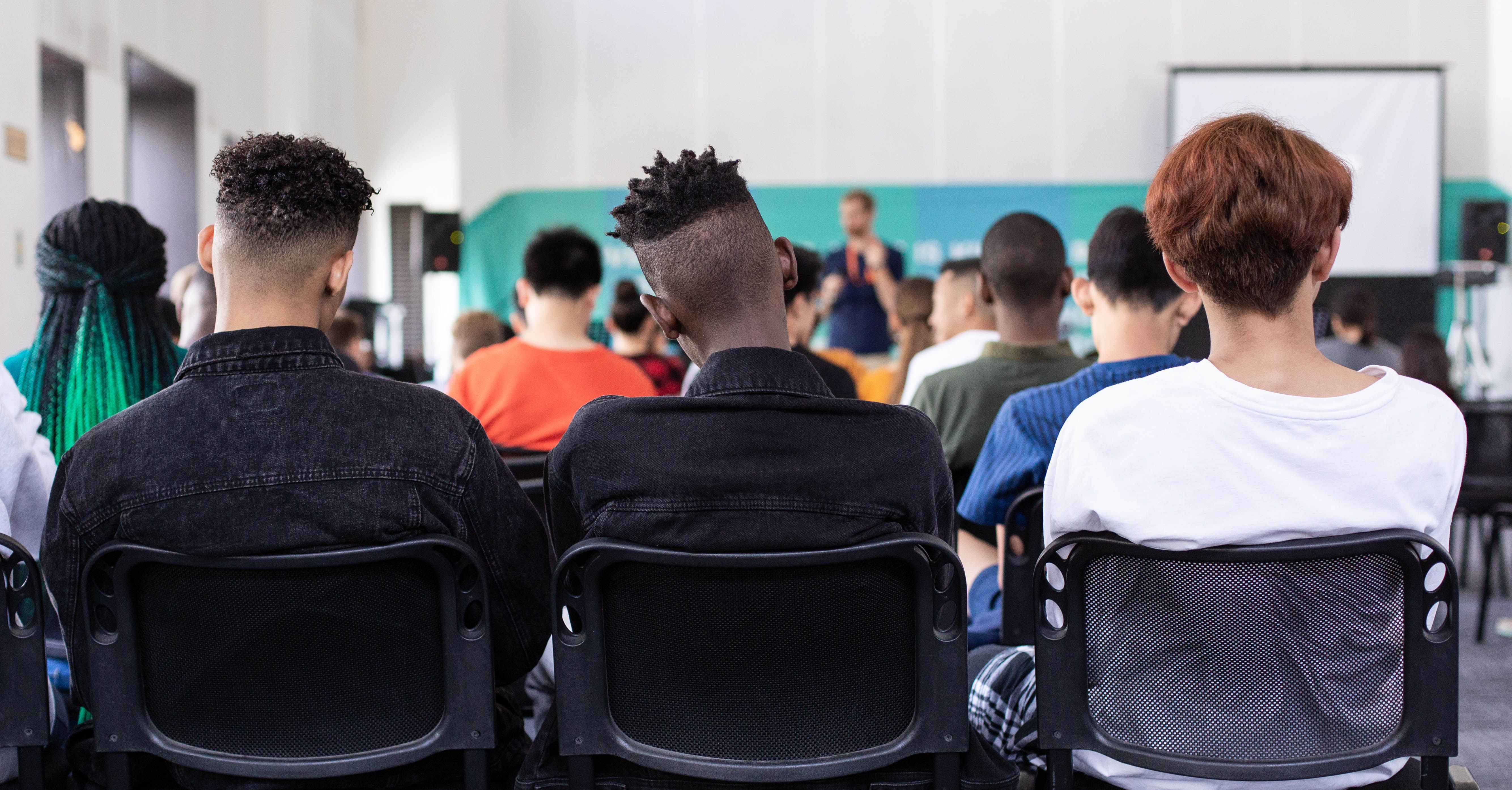 A group of teens sit together in a classroom.