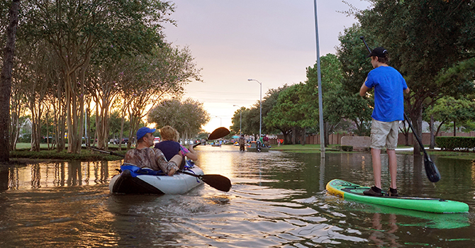family canoeing down flooded road in Houston, Texas