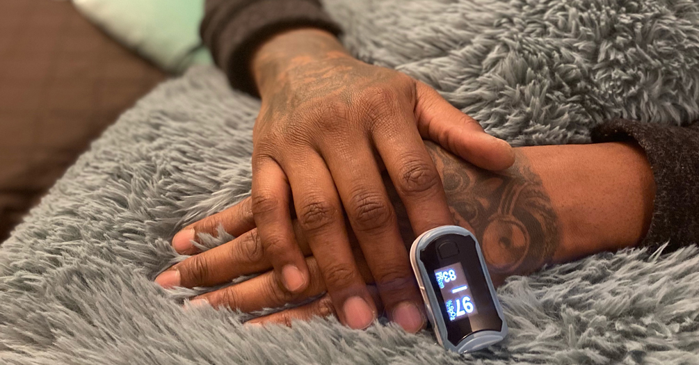 Black patient checking blood oxygen levels with a pulse oximeter