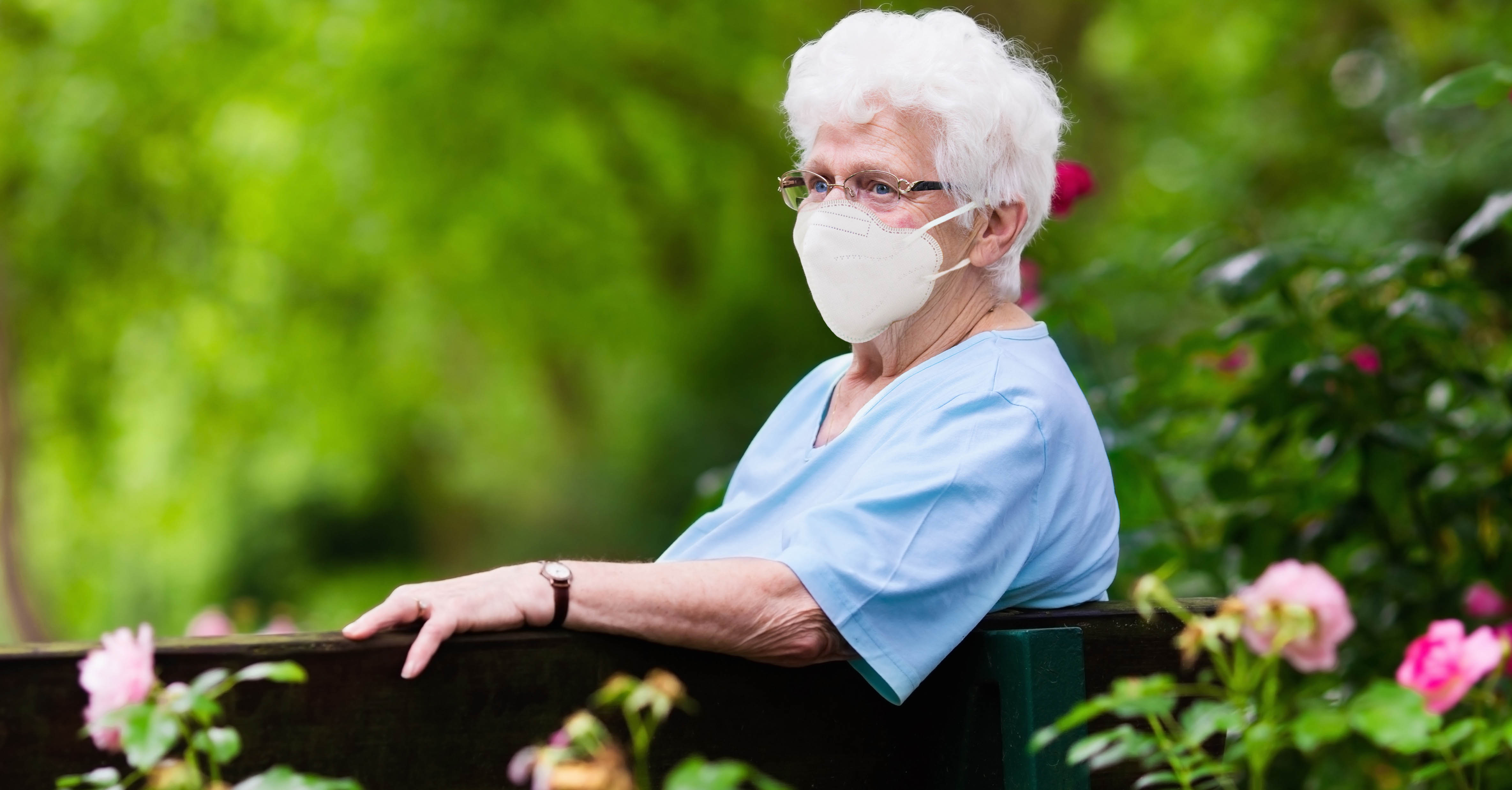 An elderly woman wears a face mask.