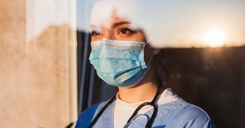 image of masked health care worker looking out of a window